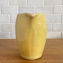 Load image into Gallery viewer, Charming vintage sunny yellow milk pitcher featuring embossed vertical scalloped pattern. Crafted by McCoy Pottery, 1964. This collectible pitcher is the perfect vessels to hold a charming bouquet of spring flowers or a lovely gift for an art pottery collector.
In vintage condition, no chips/cracks/repairs, age-related crazing and staining, manufacturer's glaze pops. Maker's mark.
Measures 6 x 3 1/2 x 5 1/8 inches