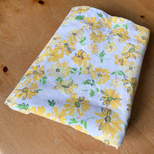 Load image into Gallery viewer, Vintage yellow daisy flat double Muslin cotton bed sheet featuring a pattern of yellow daisy flowers accented with black and green on white ground. Crafted by Dan River, USA, 1970s. A beautiful addition to your retro bedding decor. Easily repurpose for crafting, quilting or dressmaking.
In excellent vintage condition, no stains/tears.
Measures 81 x 108 inches