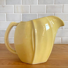Load image into Gallery viewer, Charming vintage sunny yellow tulip pitcher. Crafted by McCoy Pottery, 1940s. This collectible pitcher is the perfect vessels to hold a charming bouquet of spring flowers or a lovely gift for an art pottery collector.
In as found vintage condition, chip to the rim and handle, tight horizontal hairline crack on handle, age-related crazing, manufacturer's glaze pops. Maker's mark.
Measures 8 1/4 x 3 1/2 x 6 inches