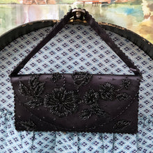 Load image into Gallery viewer, Gorgeous vintage mid-century era handmade black satin evening bag, adorned in a floral pattern of black glass beads with snap closure. This versatile bag has detachable strap allowing it be worn as a purse or clutch. The interior is lined with black satin and has a large zippered pocket. Crafted by Contessa Francesca, Hong Kong, 1950s. This generous sized bag accommodates a cell phone and other necessities for your evening affair.
Measures 8 1/2 x 1 1/4 x 4 inches (without handle), strap handle 14 inches
