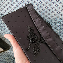 Load image into Gallery viewer, Gorgeous vintage mid-century era handmade black satin evening bag, adorned in a floral pattern of black glass beads with snap closure. This versatile bag has detachable strap allowing it be worn as a purse or clutch. The interior is lined with black satin and has a large zippered pocket. Crafted by Contessa Francesca, Hong Kong, 1950s. This generous sized bag accommodates a cell phone and other necessities for your evening affair.
Measures 8 1/2 x 1 1/4 x 4 inches (without handle), strap handle 14 inches