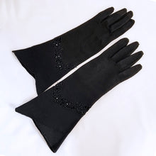 Load image into Gallery viewer, Vintage formal black cotton evening gloves featuring black glass seed bead and cutwork detail with split cuff. The workmanship is impeccable. Likely made in Europe, 1950s. Gorgeous and elegant!
In like new condition, free from stains/tears.
Measures 3 1/8 inches at the widest part of the hand, 4 1/2 inches at the cuff and 12 inches in length.