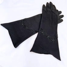 Load image into Gallery viewer, Vintage formal black cotton evening gloves featuring black glass seed bead and cutwork detail with split cuff. The workmanship is impeccable. Likely made in Europe, 1950s. Gorgeous and elegant!
In like new condition, free from stains/tears.
Measures 3 1/8 inches at the widest part of the hand, 4 1/2 inches at the cuff and 12 inches in length.