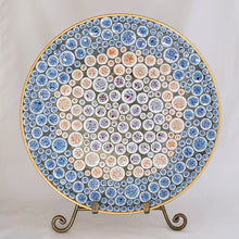 Load image into Gallery viewer, Front view of a vintage 1950s mid-century mosaic tile dish displayed on a brass easel stand, showing circular blue, white, rust and purple tiles with a gold rim