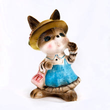 Load image into Gallery viewer, Adorable vintage figural brown bunny rabbit coin bank dressed in blue with a pink purse and yellow hat. Unmarked but likely made in Japan or Taiwan, circa 1970s. In great vintage condition with a flea bite to one of the feet. Measures approximately 6" tall.