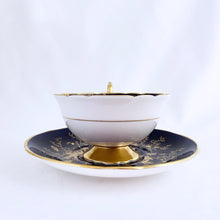 Load image into Gallery viewer, This vintage "Cairo" bone china teacup and saucer is absolutely stunning! Both the cup and saucer are glazed in cobalt blue and overlaid with gold gilt birds, butterflies and florals with a white exterior and gold gilt trim. Produced by Coalport, England, circa 1950. In good condition, free from chips, cracks and repairs. Teacup measures 4" x 2-1/8" | Saucer measures 5-3/4"