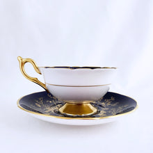Load image into Gallery viewer, This vintage "Cairo" bone china teacup and saucer is absolutely stunning! Both the cup and saucer are glazed in cobalt blue and overlaid with gold gilt birds, butterflies and florals with a white exterior and gold gilt trim. Produced by Coalport, England, circa 1950. In good condition, free from chips, cracks and repairs. Teacup measures 4" x 2-1/8" | Saucer measures 5-3/4"