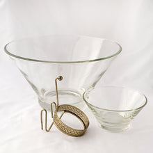 Load image into Gallery viewer, Fabulous vintage mid-century "Modernistic" clear glass chip and dip set with brass-toned metal hanger bracket. The small bowl fits nicely in the hanger bracket which secures it onto the large bowl. Made by Anchor Hocking Glass Co., USA, circa 1950. Entertain in style for movie/game nights or your next party! In excellent condition, free from chips or cracks. Large bowl measures 10 7/8 inches x 5 3/4 inches Small bowl Measures 5 1/4 x 2 1/2 inches
