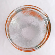 Load image into Gallery viewer, Bring a little sunshine to table with this retro glass carafe decorated with vibrant oranges and white flowers. Produced by Anchor Hocking Glass Company USA. Production began on this pattern in 1950s. This piece was manufactured in 1987. This carafe or pitcher is perfect for juice, iced tea, lemonade, water or mix up some cocktails! In excellent condition, no chips or cracks and the colour is vibrant orange and green. Measures 4 x 8 5/8 inches