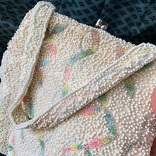 Load image into Gallery viewer, Unique handmade vintage mid-century era evening bag adorned in cream glass seed beads and ribbons of multi-colour pastel embroidery, topped with a matching beaded strap and silver toned metal kiss closure. The interior is lined with cream satin with open pocket. The bag is large enough for a cell phone, credit cards/cash, compact/lipstick. Produced in Japan. An absolutely stunning piece that would make an incredible bridal accessory!
Excellent used vintage condition.
