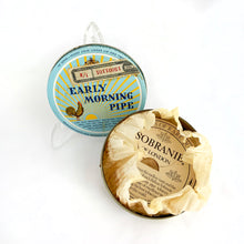 Load image into Gallery viewer, Vintage Early Morning Pipe tobacco tin with original interior wrap and tariff sticker. The lid has a great graphic of a sunrise and a rooster crowing on a pale blue background. Produced by Alfred Dunhill in England. In good vintage condition with minor wear. Measures 4 x 1 inches