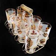 Load image into Gallery viewer, Set of eight mid-century vintage Golden Foliage highball glasses in brass carrying caddy with spiral handle. Produced by the Libbey Glass Company between 1953 - 1978. These glasses will elevate any bar cart and are perfect for any occasion or cocktail! Great vintage condition. The glasses are free from chips/cracks. Minor wear present to the gold on the rim. Each glass measures 2-3/4" x 5-1/2" (12oz)