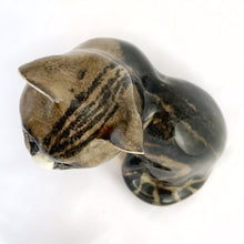 Load image into Gallery viewer, Highly desirable and collectible, this sweet vintage ceramic seated grey/brown striped tabby cat figurine has striking amber cathedral glass eyes (if you look at the eyes and move, the eyes will follow you). Produced by artist Mike Hinton, England (retired from Winstanley). In excellent condition, free from chips/cracks. Signed by the artist and marked with the # 33 and England. Dimensions: 5-1/4" x 3-3/4" x 5-3/4"