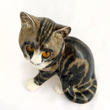 Load image into Gallery viewer, Highly desirable and collectible, this sweet vintage ceramic seated grey/brown striped tabby cat figurine has striking amber cathedral glass eyes (if you look at the eyes and move, the eyes will follow you). Produced by artist Mike Hinton, England (retired from Winstanley). In excellent condition, free from chips/cracks. Signed by the artist and marked with the # 33 and England. Dimensions: 5-1/4" x 3-3/4" x 5-3/4"