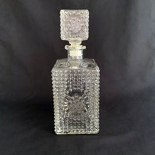 Load image into Gallery viewer, Vintage clear glass liquor decanter with an overall hobnail pattern and circular medallion on each side, topped with a square hobnail stopper. A fabulous addition to your bar cart for your favourite liquor, or as a fruit juice decanter on your brunch buffet.
Excellent condition, no chips. Stopper has a plastic insert for a tight seal.
Measures 3 5/8 x 3 5/8 x 9 1/2 inches