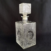 Load image into Gallery viewer, Vintage clear glass liquor decanter with an overall hobnail pattern and circular medallion on each side, topped with a square hobnail stopper. A fabulous addition to your bar cart for your favourite liquor, or as a fruit juice decanter on your brunch buffet.
Excellent condition, no chips. Stopper has a plastic insert for a tight seal.
Measures 3 5/8 x 3 5/8 x 9 1/2 inches