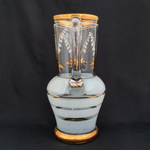Load image into Gallery viewer, Vintage blown glass pitcher beautifully detailed with white Lily-of-the-Valley with gold leaves along with soft white and gold bands and applied blown glass handle. The perfect piece of serveware for spring and summer gatherings! Crafted in the Czech Republic, 1950s.
In excellent condition, no chips.
Measures 5 x 11 1/8 inches