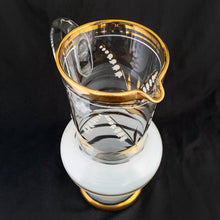 Load image into Gallery viewer, Vintage blown glass pitcher beautifully detailed with white Lily-of-the-Valley with gold leaves along with soft white and gold bands and applied blown glass handle. The perfect piece of serveware for spring and summer gatherings! Crafted in the Czech Republic, 1950s.
In excellent condition, no chips.
Measures 5 x 11 1/8 inches