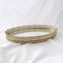 Load image into Gallery viewer, This elegant vintage Hollywood Regency style oval-shaped mirrored dresser vanity tray, featuring brass ormolu details, is perfect for displaying perfume bottles, trinket dishes, and makeup. Alternately, hang it on the wall to add glitz and glamour to your décor. In excellent condition. Measures 12 x 9 x 1 1/4 inches