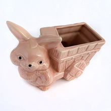 Load image into Gallery viewer, Adorable vintage pink ceramic planter of a bunny rabbit pulling a wagon. Made in Taiwan, circa 1960. Fill this pretty planter with your favourite houseplant or succulents. Could be filled with some delicious confections for a lovely Easter gift or display! In excellent condition, free from chips/cracks/repairs. 6 1/2 x 3 1/2 x 5 inches