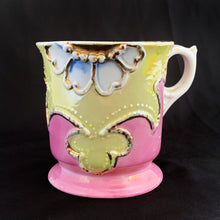 Load image into Gallery viewer, Vintage wood handled shaving brush and white porcelain shaving mug with raised slip details painted in pink, yellow and blue, highlighted in gold. Use as intended or repurpose as a toothbrush or make-up brush holder. Impressed mark "510" and painted "13". In good vintage condition, no cracks/repairs. The edge on the soap side is worn. Dimensions: 3-1/8" x 3"