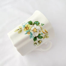 Load image into Gallery viewer, Treat yourself to a cuppa in this lovely feminine shaped fine bone china mug featuring beautiful white and yellow flowers with green leaves on white bone china. Crafted by Royal Grafton, England, circa 1970s. Grafton made these mugs with many floral designs — collect them all! In excellent condition, no chips, cracks or crazing. Marked on the bottom with "Royal Grafton, Fine Bone China, Made in England". Measures 3 1/4 x 3 1/4 inches