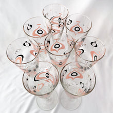 Load image into Gallery viewer, Make any day a special occasion with these highly collectible and hard to find vintage mid-century atomic style Seville pilsner or champagne glasses. Decorated with a graphic geometric design in swirls of pink, charcoal black and gold, they remind us of a New Year's eve party and are perfect for that midnight champagne toast! Bonus, they come in the original wood handled brass caddy.