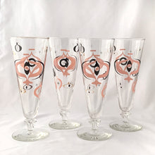 Load image into Gallery viewer, Make any day a special occasion with these highly collectible and hard to find vintage mid-century atomic style Seville pilsner or champagne glasses. Decorated with a graphic geometric design in swirls of pink, charcoal black and gold, they remind us of a New Year's eve party and are perfect for that midnight champagne toast! Bonus, they come in the original wood handled brass caddy.