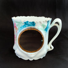 Load image into Gallery viewer, This vintage white porcelain shaving mug begs the question, "who is the fairest of them all" with it's unique round mirror edged in enamel or copper. The mug is hand painted with lovely pink and yellow roses and decorative edge with gold. Use as intended or repurpose as a toothbrush or make-up brush holder. Stamped with maker's mark, "Royal Coburg, Germany". In used vintage condition, minor chips at the edge no cracks/repairs. Measures 3 1/8 x 3 inches