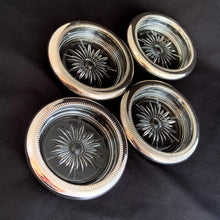Load image into Gallery viewer, Vintage set of 4 silver plate rimmed crystal coasters featuring a cut sunburst and finished in a silver plate rolled rim with beaded detail. Perfect to protect your furniture from water marks. A super sparkly and elegant resting place for your beverage!
In excellent condition. In original box. Crafted by Leonard in Italy.
Each coaster measures 4 x 3/4 inches
