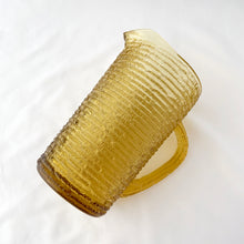 Load image into Gallery viewer, Enjoy freshly made beverages with this vintage "Soreno Gold" pressed glass pitcher. Made with a textured bark pattern and a luminous gold colour, it's perfect for serving juice, lemonade, or ice tea. Produced by Anchor Hocking Glass Company, USA between 1966-1970. In excellent condition - free from chips or cracks. Measures 4 x 7 inches Capacity of 1 litre or quart