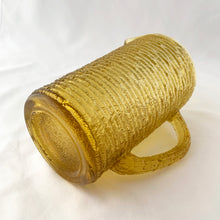 Load image into Gallery viewer, Enjoy freshly made beverages with this vintage "Soreno Gold" pressed glass pitcher. Made with a textured bark pattern and a luminous gold colour, it's perfect for serving juice, lemonade, or ice tea. Produced by Anchor Hocking Glass Company, USA between 1966-1970. In excellent condition - free from chips or cracks. Measures 4 x 7 inches Capacity of 1 litre or quart
