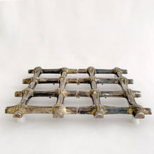 Load image into Gallery viewer, This beautiful vintage Hollywood Regency silver plated bamboo tiki style trivet conveniently extends to accommodate larger dishes and its rubber feet will protect surfaces. Sticker on the bottom reads "Silver Plated Zinc". Crafted in Hong Kong, circa 1950s. A great way to protect your furniture from getting marked by hot ovenware! Measures 7 1/4 x 7 1/4 and extends to 10 1/4 inches
