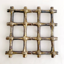 Load image into Gallery viewer, This beautiful vintage Hollywood Regency silver plated bamboo tiki style trivet conveniently extends to accommodate larger dishes and its rubber feet will protect surfaces. Sticker on the bottom reads "Silver Plated Zinc". Crafted in Hong Kong, circa 1950s. A great way to protect your furniture from getting marked by hot ovenware! Measures 7 1/4 x 7 1/4 and extends to 10 1/4 inches