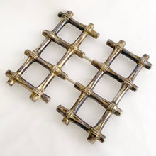 Load image into Gallery viewer, This beautiful vintage Hollywood Regency silver plated bamboo tiki style trivet conveniently extends to accommodate larger dishes and its rubber feet will protect surfaces. Sticker on the bottom reads "Silver Plated Zinc". Crafted in Hong Kong, circa 1950s. A great way to protect your furniture from getting marked by hot ovenware! Measures 7 1/4 x 7 1/4 and extends to 10 1/4 inches