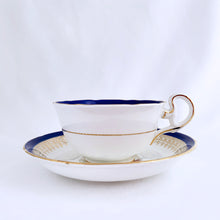 Load image into Gallery viewer, This vintage bone china teacup and saucer is absolutely stunning! Both the cup and saucer are glazed in white with a blue band, gold geometric pattern and rim with a central bouquet of colourful flowers. Produced by Royal Grafton, England, circa 1950 - 1956. In excellent condition, free from chips, cracks and repairs. Pattern number 1781 marked on the bottom of the teacup. Teacup measures 3-7/8" x 2" | Saucer measures 5-5/8"