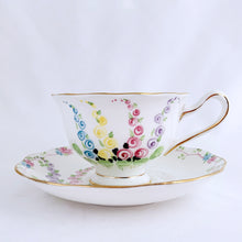 Load image into Gallery viewer, This antique bone china footed teacup and saucer is so sweet! Both the cup and saucer have a lovely scalloped edge with hand painted whimsical pastel coloured foxglove flowers and rimmed with gold gilt. Produced by Royal Albert, England, circa 1917 - 1927. In good condition. Teacup measures 3 3/4 x 2 3/8 inches | Saucer measures 5 1/2 inches