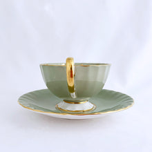 Load image into Gallery viewer, vintage bone china teacup and saucer with a lovely scalloped shape. The cup is a lovely shade of celadon green, interior celadon band is overlaid with a complex gold pattern with a central bouquet of colourful flowers. Saucer is celadon green with a white centre and gold gilt rim. Produced by Aynsley, England, circa 1939. In excellent condition, free from chips, cracks and repairs. Pattern number C1557 with maker's marks. Teacup measures 3-1/2" x 2-1/4" | Saucer measures 5-5/8"