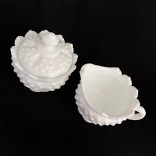 Load image into Gallery viewer, Vintage white milk glass is the epitome of simple elegance! This is a scalloped creamer and lidded sugar bowl in the "Hobnail" pattern. Produced by Fenton, post 1970. Marked. The creamer is in excellent condition, free from chips or cracks. The sugar bowl has a chip on the side of one of the scalloped points...it's not rough or really noticeable thanks to the piece being white. Creamer measures 4" 3-1/2", sugar w/ lid measures 4" x 4-3/4"