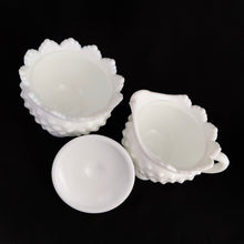 Load image into Gallery viewer, Vintage white milk glass is the epitome of simple elegance! This is a scalloped creamer and lidded sugar bowl in the "Hobnail" pattern. Produced by Fenton, post 1970. Marked. The creamer is in excellent condition, free from chips or cracks. The sugar bowl has a chip on the side of one of the scalloped points...it's not rough or really noticeable thanks to the piece being white. Creamer measures 4" 3-1/2", sugar w/ lid measures 4" x 4-3/4"