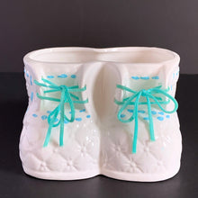 Load image into Gallery viewer, Vintage white booties ceramic planter with real blue laces and blue stitching detail. Crafted by China Ceramic Co., Taiwan, 1970s/80s. Perfect as nursery decor for a succulent or to store baby accessories.
In excellent condition, no chips or cracks.
Marked on the bottom with a 'CJ' in a circle and sticker.
Measures 6 1/2 x 4 1/2 x 3 1/2 inches