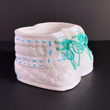 Load image into Gallery viewer, Vintage white booties ceramic planter with real blue laces and blue stitching detail. Crafted by China Ceramic Co., Taiwan, 1970s/80s. Perfect as nursery decor for a succulent or to store baby accessories.
In excellent condition, no chips or cracks.
Marked on the bottom with a 'CJ' in a circle and sticker.
Measures 6 1/2 x 4 1/2 x 3 1/2 inches