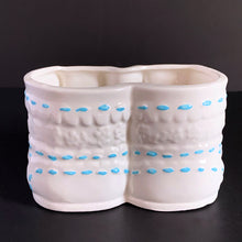 Load image into Gallery viewer, Vintage white booties ceramic planter with real blue laces and blue stitching detail. Crafted by China Ceramic Co., Taiwan, 1970s/80s. Perfect as nursery decor for a succulent or to store baby accessories.
In excellent condition, no chips or cracks.
Marked on the bottom with a 'CJ' in a circle and sticker.
Measures 6 1/2 x 4 1/2 x 3 1/2 inches