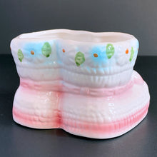 Load image into Gallery viewer, Vintage white baby booties ceramic planter features pink bows, white and blue flowers. Crafted by Nancy Pew Giftware, Taiwan, 1970s. An adorable accessory for a baby nursery!
In excellent condition, no chips, cracks or repairs. Maker's mark and sticker.
Measures 4 x 4 x 3 inches
