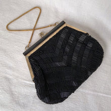Load image into Gallery viewer, Stunning vintage art deco style beaded evening bag features black bugle and round glass beads in a fringe pattern, black silk lining, gold toned chain and kiss closure. Crafted by Artel, Hong Kong 1950s. Take your fashion to the next level with this elegant accessory.
In vintage condition, with a few beads missing.