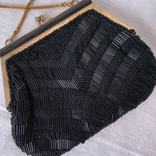 Load image into Gallery viewer, Stunning vintage art deco style beaded evening bag features black bugle and round glass beads in a fringe pattern, black silk lining, gold toned chain and kiss closure. Crafted by Artel, Hong Kong 1950s. Take your fashion to the next level with this elegant accessory.
In vintage condition, with a few beads missing.