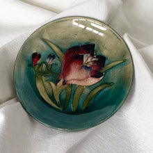Load image into Gallery viewer, Vintage slip glazed and hand painted "African Lily' art pottery pin dish in tones of teal, green, burgundy and blue. Designed by Walter Moorcroft and produced by Moorcroft Pottery, England, circa 1950 In excellent condition, free from chips/cracks/repairs, crazing present. Impressed with "Moorcroft" and "Made in England". Measures 4-1/2" x 3/4"