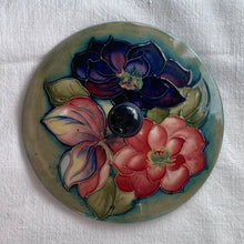 Load image into Gallery viewer, Vintage mid-century "Clematis" lidded dish with green ground lid and teal/blue ground on bowl's interior and deep blue on the exterior of the bowl. The colours are vibrant and the tube lining and hand painting are spectacular. Produced by Moorcroft Pottery, England, circa 1950s.  Measures 6-1/4" x 3-1/2"  Excellent condition. No cracks or chips. Normal crazing for a piece of this age. Impressed marks include Walter Moorcroft's signature, Potter to H.M. The Queen and Made in England.