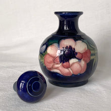 Load image into Gallery viewer, Vintage mid-century "Anemone" perfume bottle with stopper. Hand painted in the slip glaze technique in shades of purple, pink and green on a deep cobalt blue ground. Produced by Moorcroft Pottery, circa 1928-1953. In excellent condition, no chips, cracks or repairs, crazing present. Bottom shows impressed signature of Walter Moorcroft, "MADE IN ENGLAND" and Royal Warrant paper label - 'Potter To HM The Queen'. Measures 4" x 5-1/2"