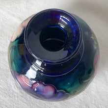 Load image into Gallery viewer, Vintage mid-century "Anemone" perfume bottle with stopper. Hand painted in the slip glaze technique in shades of purple, pink and green on a deep cobalt blue ground. Produced by Moorcroft Pottery, circa 1928-1953. In excellent condition, no chips, cracks or repairs, crazing present. Bottom shows impressed signature of Walter Moorcroft, "MADE IN ENGLAND" and Royal Warrant paper label - 'Potter To HM The Queen'. Measures 4" x 5-1/2"